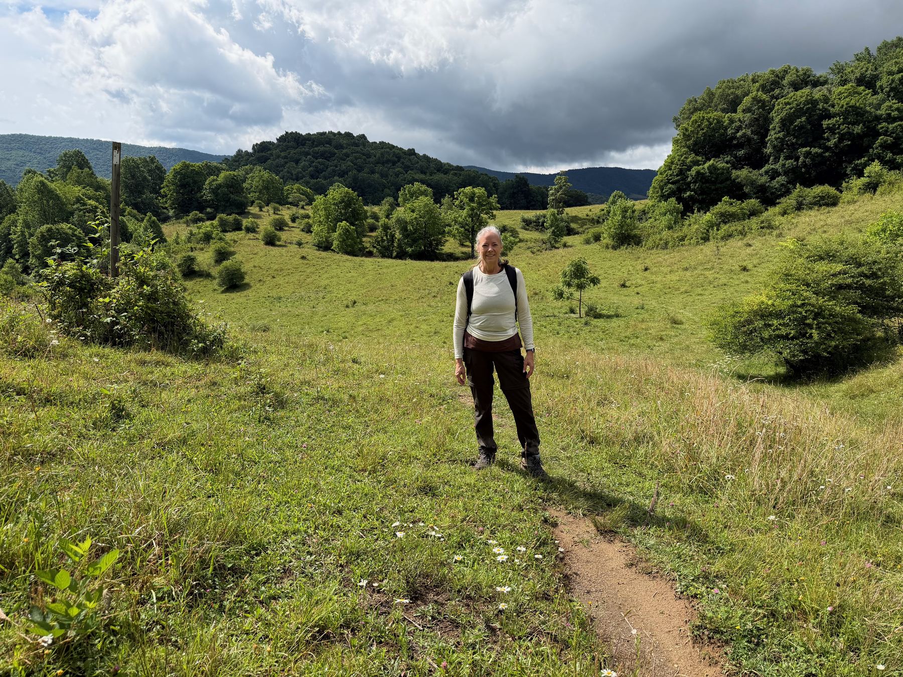 Standing on a grassy balds trail, mountains behind