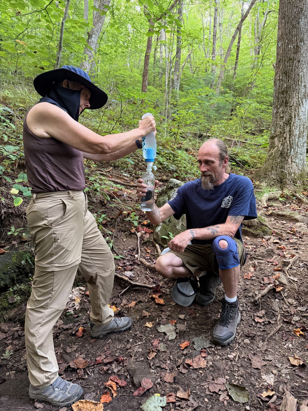 Two hikers filtering water together on the trail