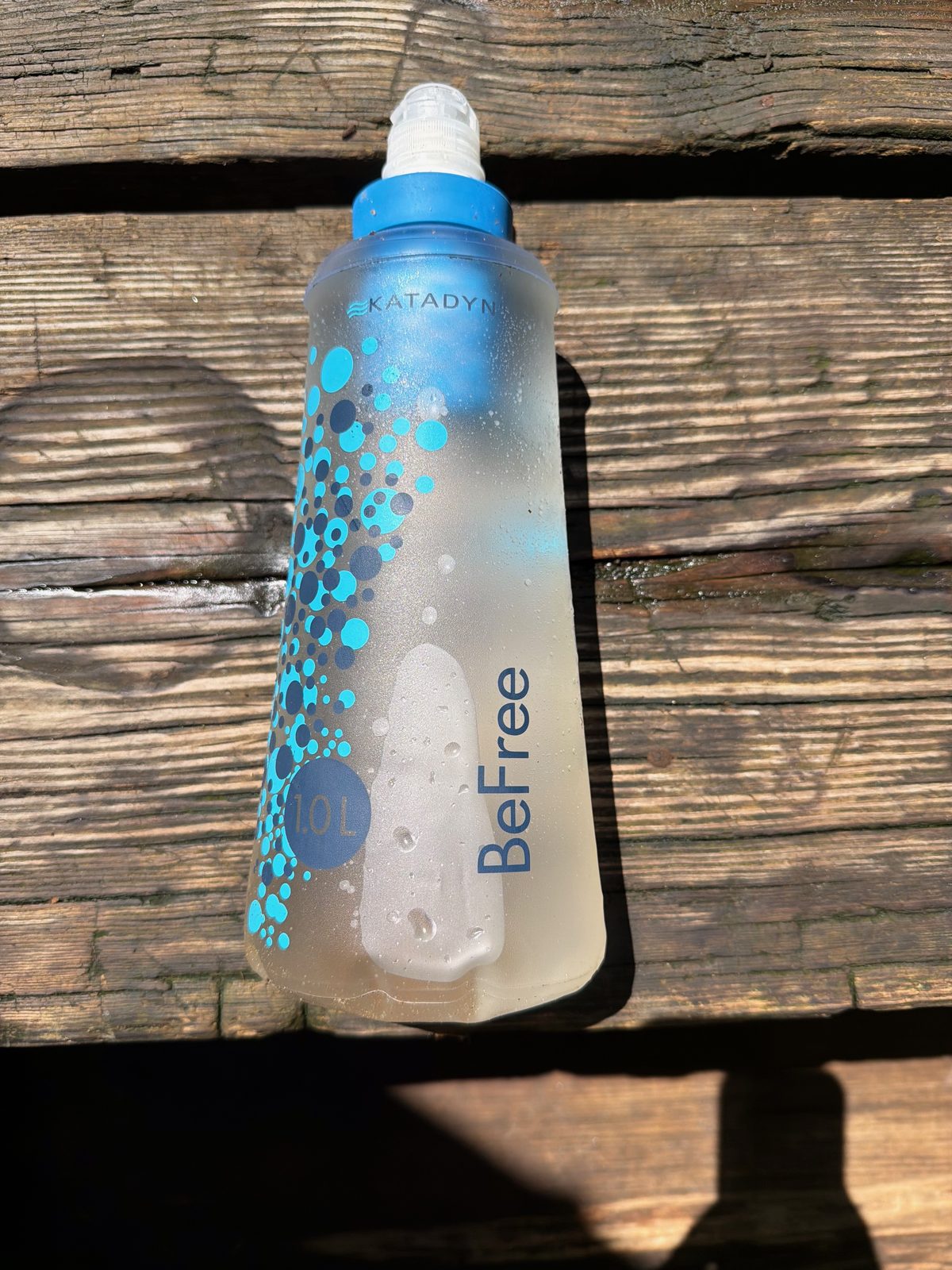 A Katadyn BeFree water filter bottle resting on a wooden trail bench