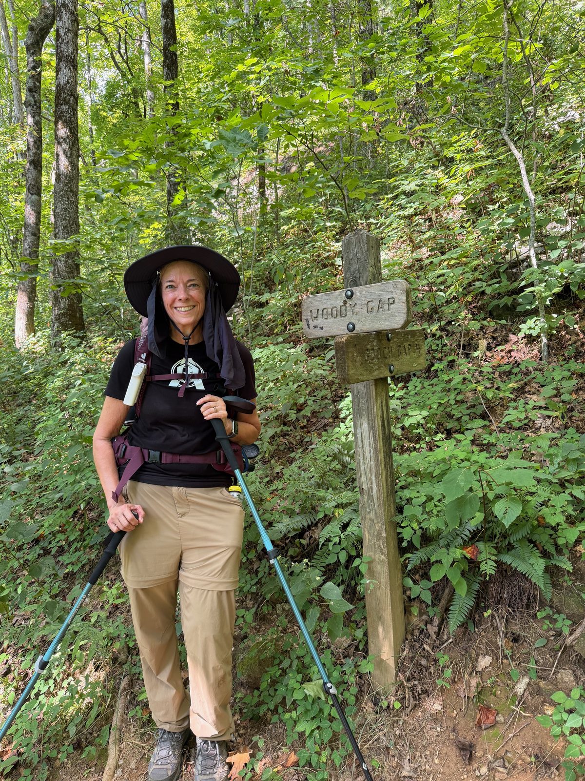 Standing next to the wooden Woody Gap trail sign